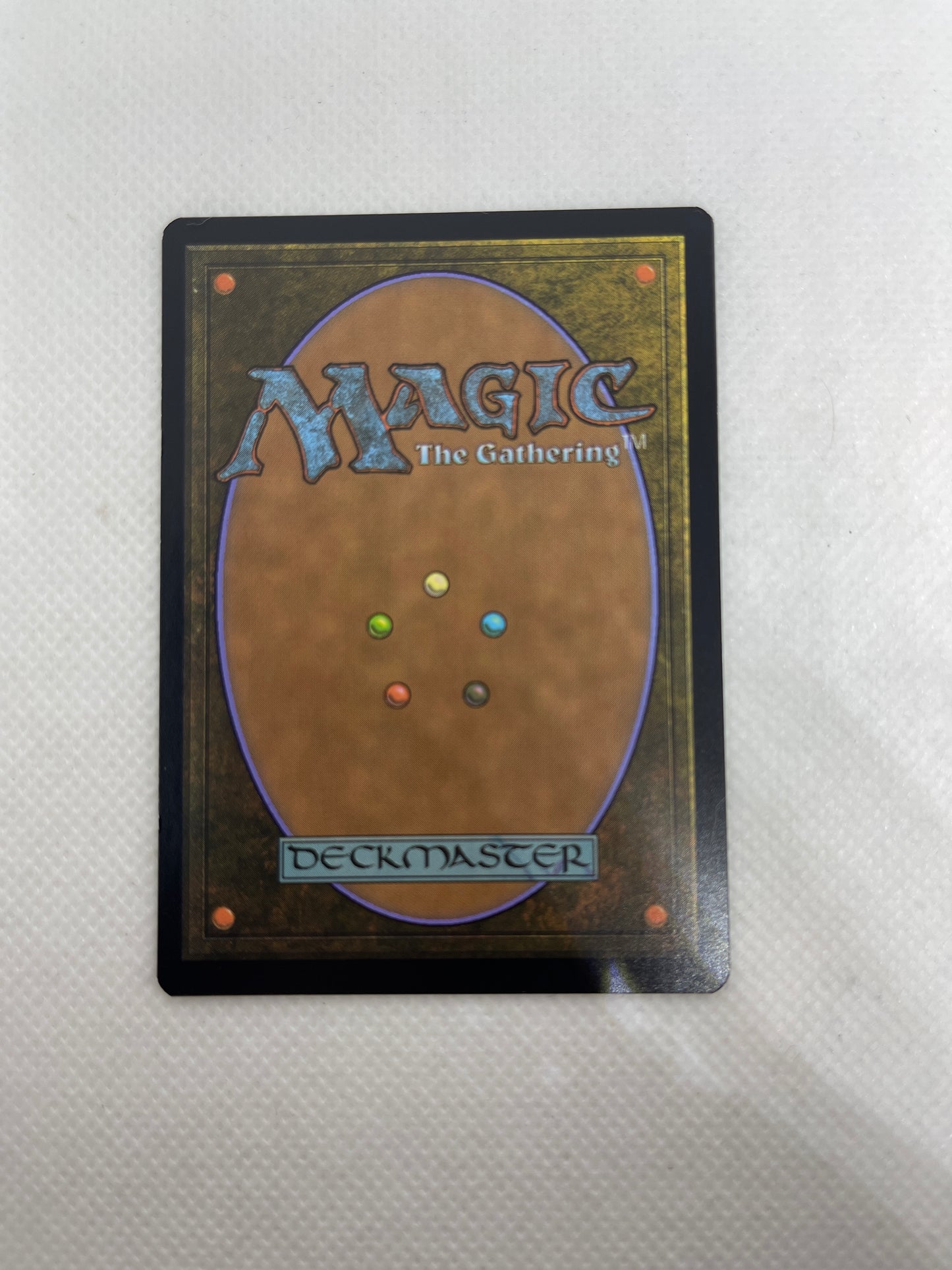 Trading card with 'Magic: The Gathering' logo and multicolored dots on a textured surface