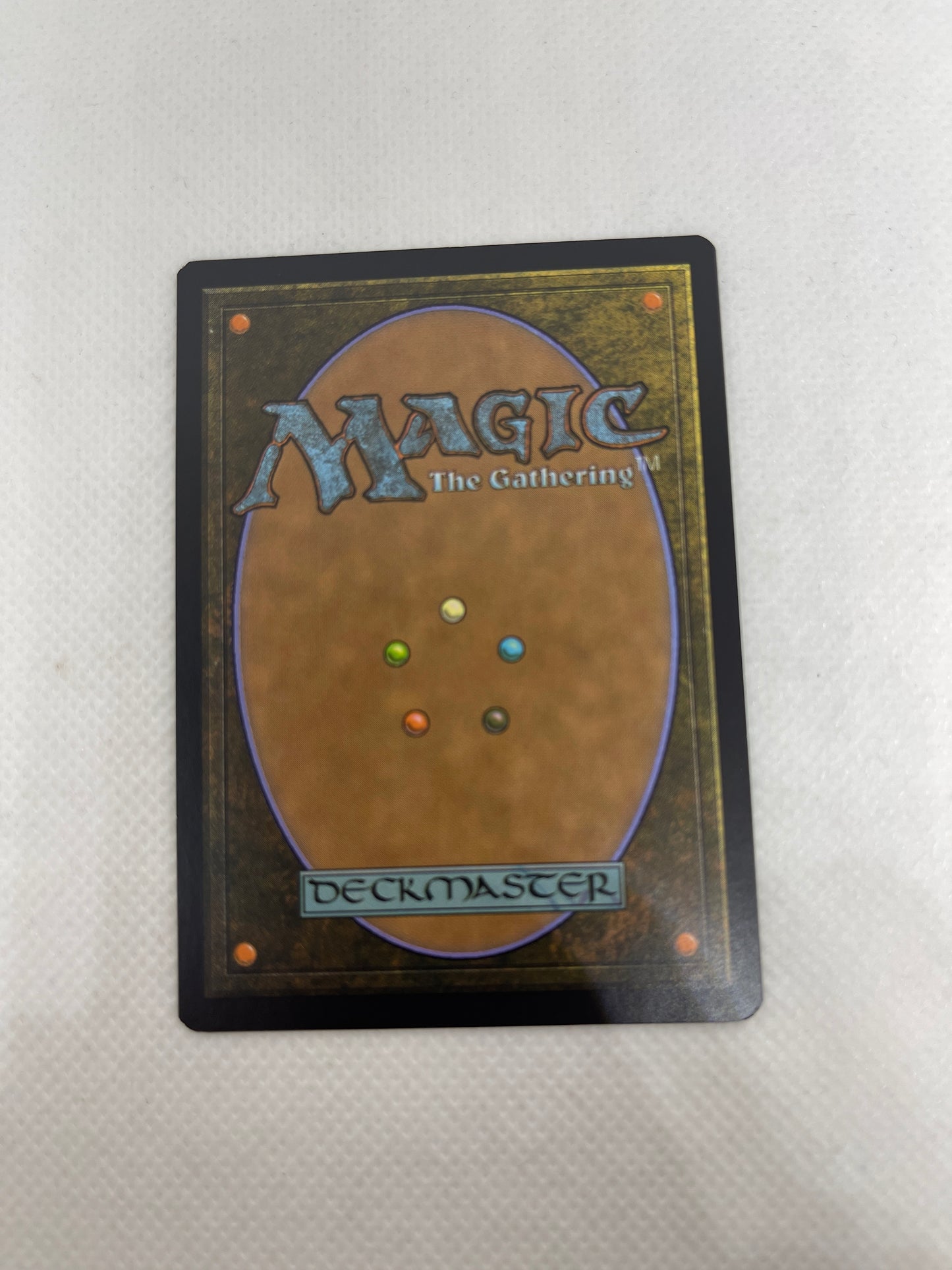 Trading card from 'Magic: The Gathering' with multicolored mana symbols on a textured surface