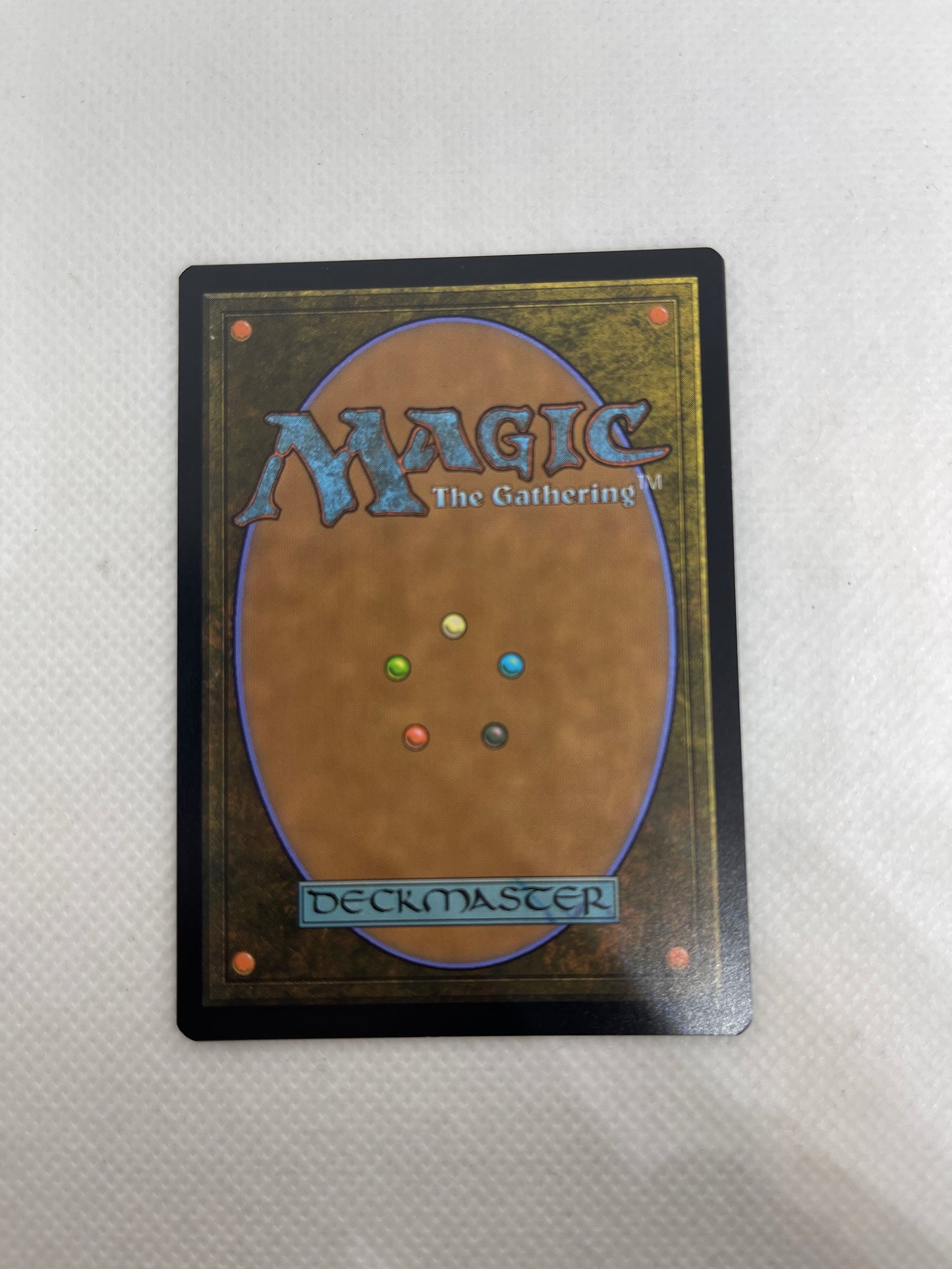 Trading card with 'Magic: The Gathering' logo and multicolored dots on a textured surface