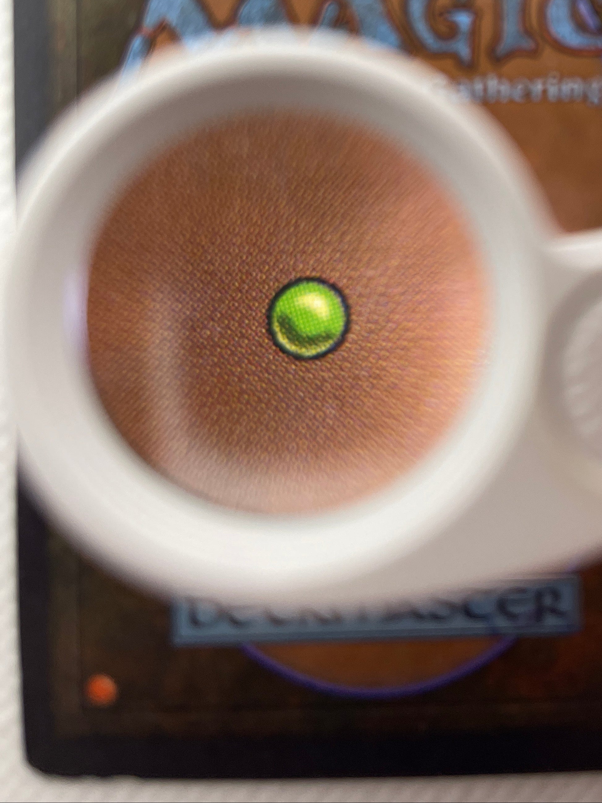 Close-up of a card with a green gemstone and 'Magic: The Gathering' branding.