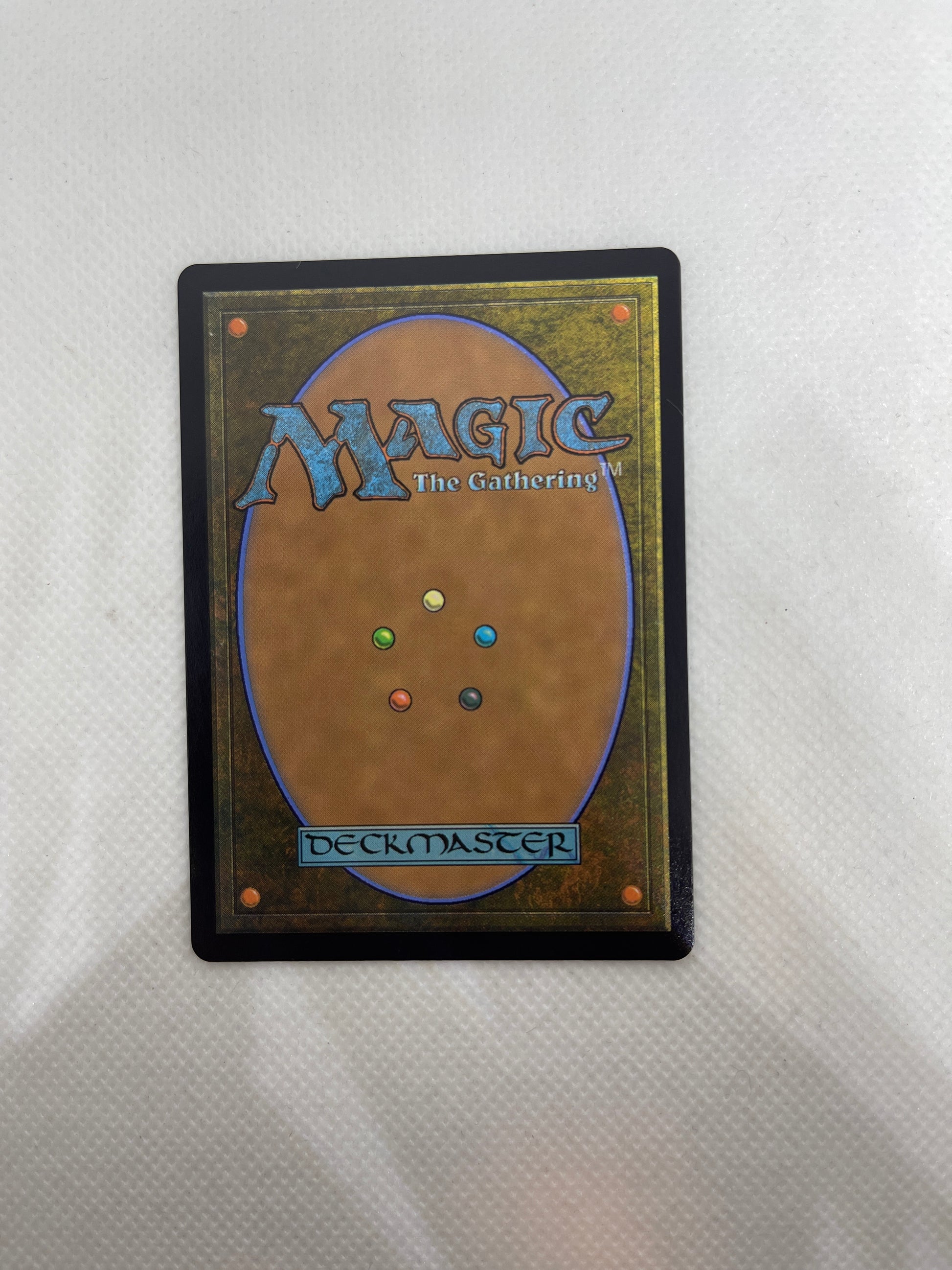 Trading card with 'Magic: The Gathering' logo and multicolored dots on a textured surface