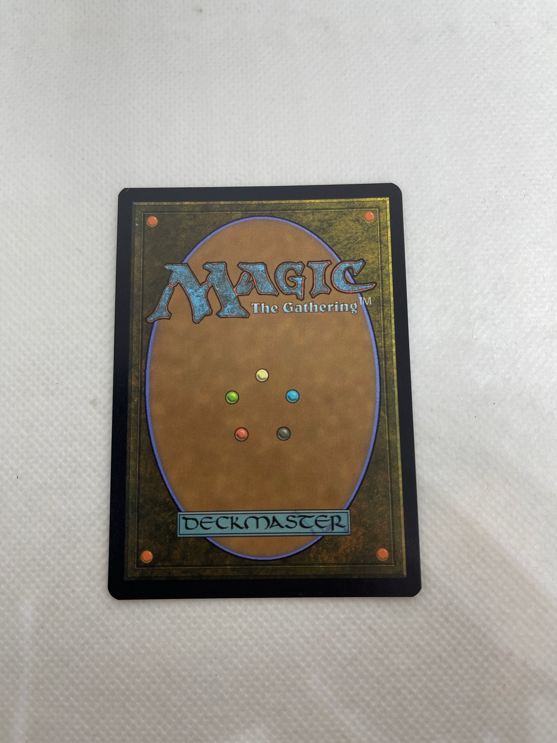 Trading card with 'Wizards of the Coast' logo and multicolored dots on a white background